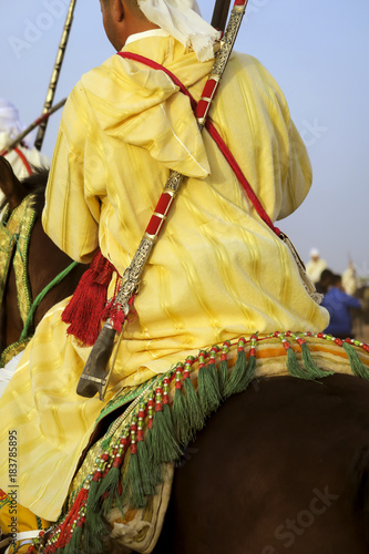 Horse Rider Wearing Moroccan Traditional Clothes Carrying His long arm gun During The Gunpowder PLay  or Tbourida In Arabic which is a traditional exhibition celebrated In Morocco. photo