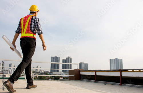 Professional Foreman wearing safety helmet hold blueprint while walking on the building deck