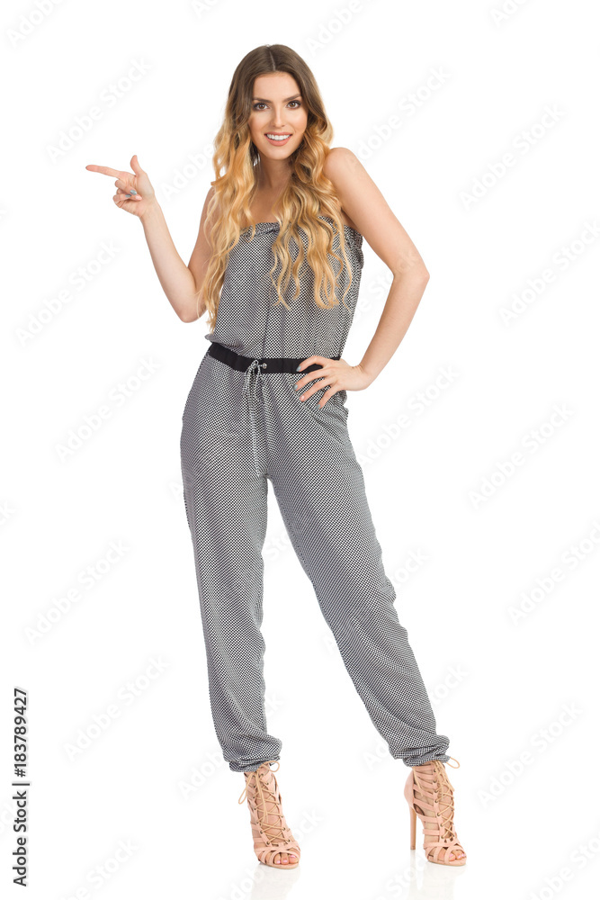 Fashion Model In Jumpsuit And High Heels Is Standing And Pointing Fashion Model In Jumpsuit And High Heels Is Standing And Pointing