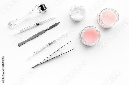 Dermatologist or cosmetologist accessories. Dermaroller, creams and mask, beauty injection, tools on white background top view copyspace