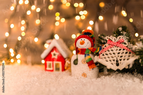Christmas decoration on a wooden background with snowman, snow and lights in the background