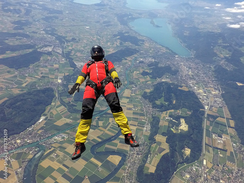 Female skydiver free falling on back above landscape