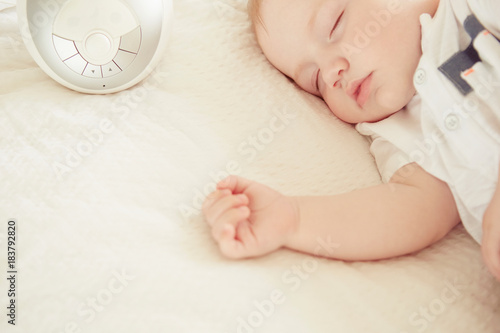 Baby boy sleeping, baby monitor on bed beside him photo