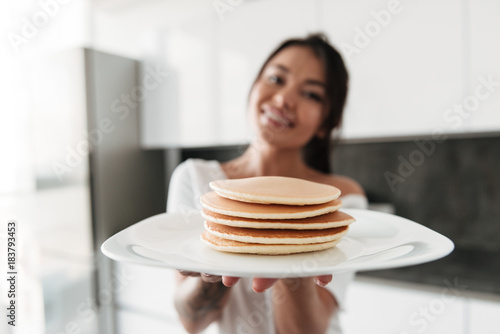 Happy young woman holding pancakes.