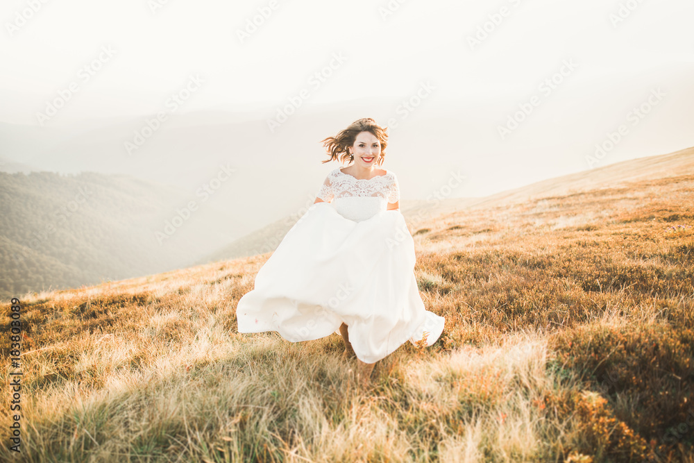 Beautiful bride with a bouquet on mountain background at sunset