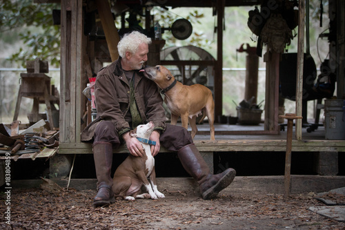 Man with pet dogs by wooden work hut