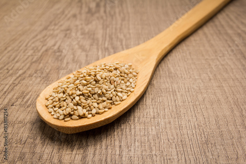 Sesame. Spoon and grains over wooden table.