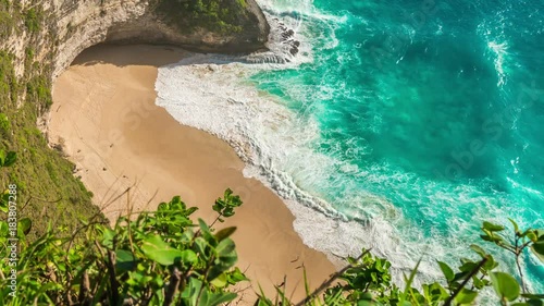 Ariel timelapse view on beach with waves and people at Kelingking Beach on Nusa Penida Island, Bali, Indonesia photo