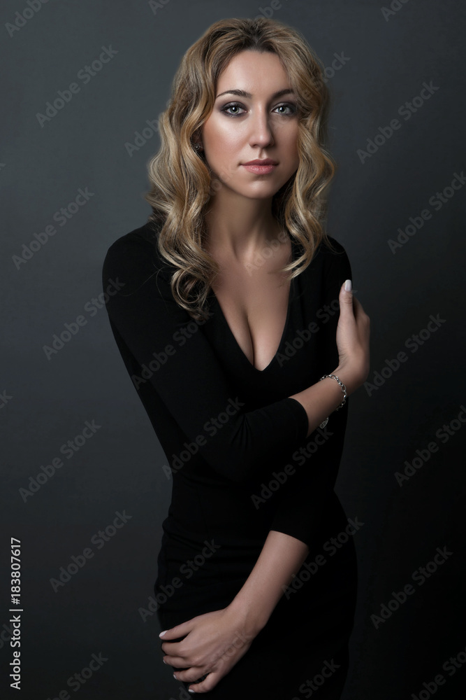 portrait of beautiful woman in black dress standing on dark background