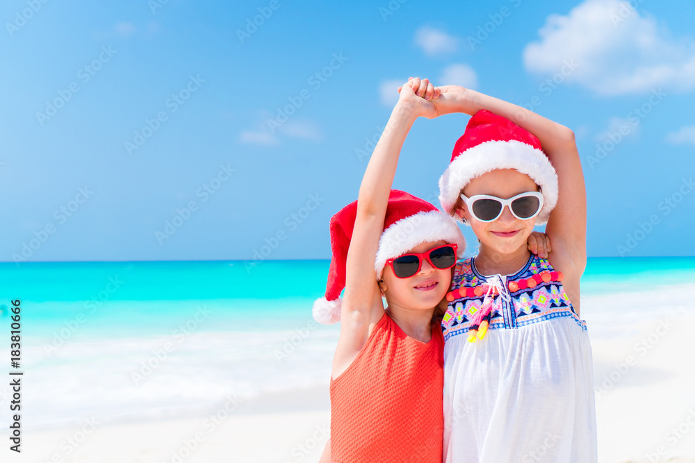 Obraz premium Adorable little kids in Santa hat during Christmas beach vacation. New Year on the beach