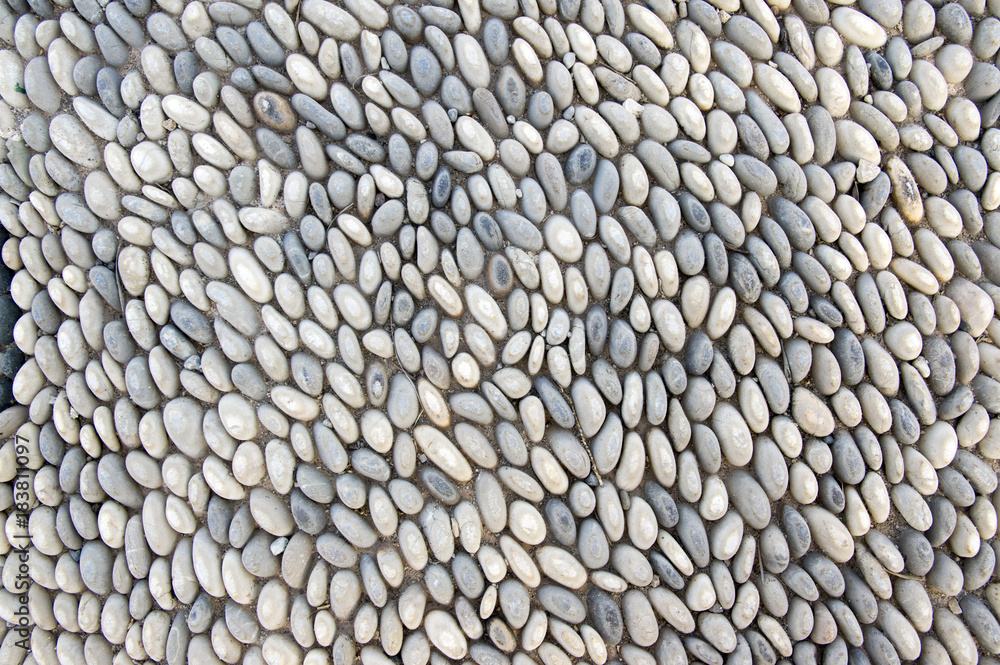 Obraz premium Detail of a walkway made of river pebbles, stone background, light grey and white colors