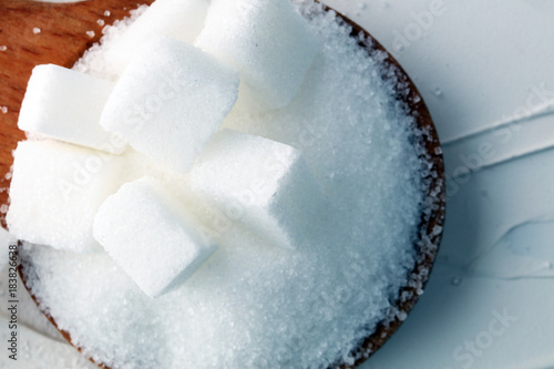 Cubes of sugar and granulated sugar with wooden spoon.