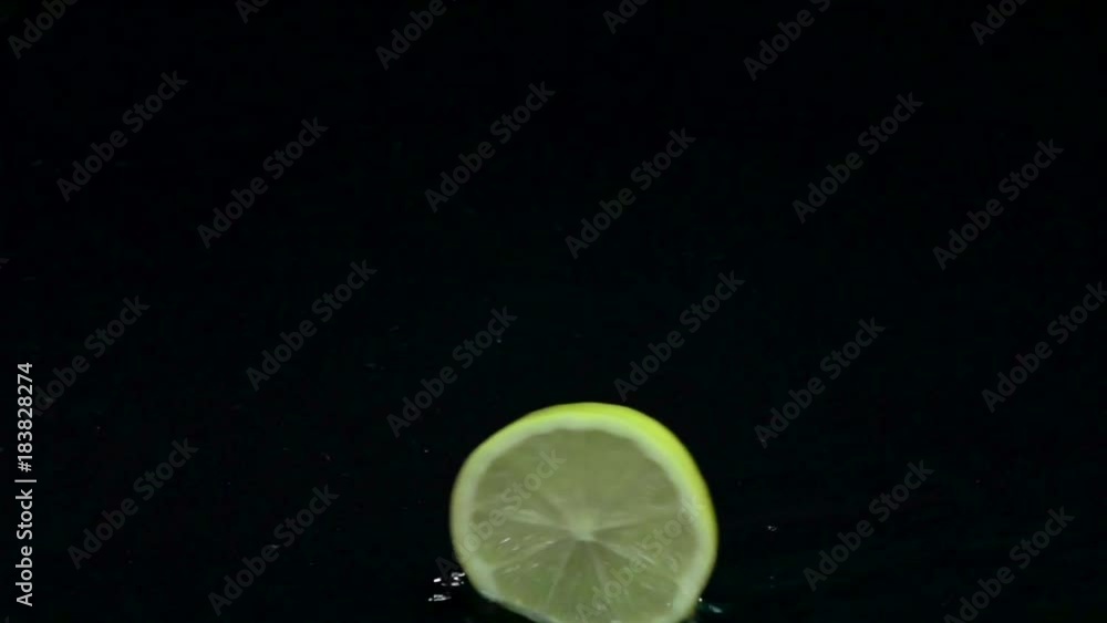 Slice of lemon roll on the water. Black background. Slow motion