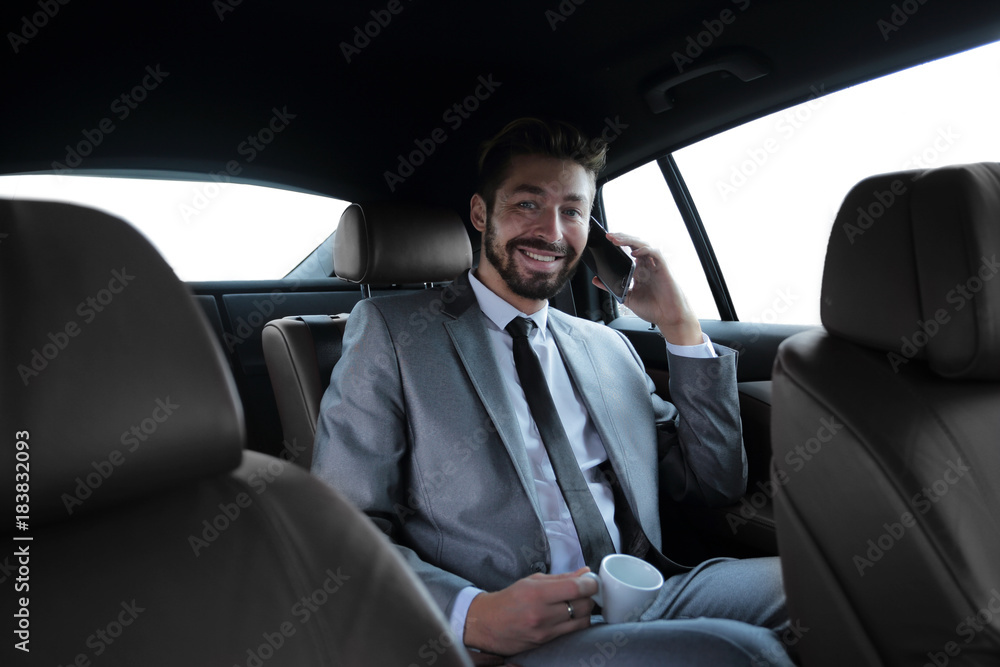 businessman sitting in car with cup and smartphone