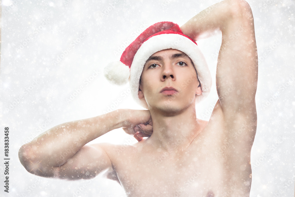 Christmas new year concept. Man with santa claus hat looking angry. Dangerous Guy with stylish hair on white background with powerful arms and torso