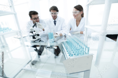 background image of scientists studying blue liquid in a flask