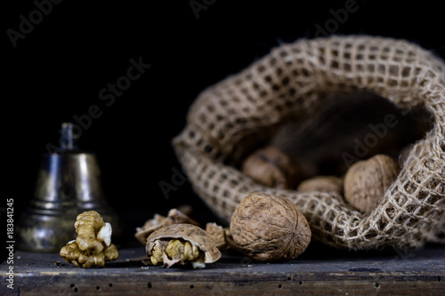 Nuts in a natural bag. A bag of nuts and a bell on an old dark wooden table.