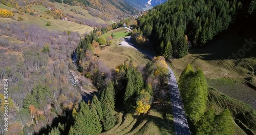 Biker on a autumn color road, Cinema 4k aerial view following a motorbike driving between mountains, on a colorful fall alp road, on a sunny autumn day, on nufenen pass, in ticino, switzerland