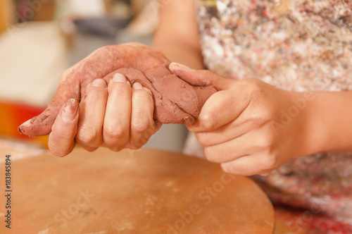 Closeup of woman ceramist hands working on sculpture on wooden table in workshop © Fotos 593