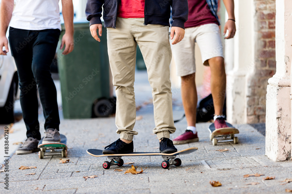 Teenage friends walking at the street with skateboards