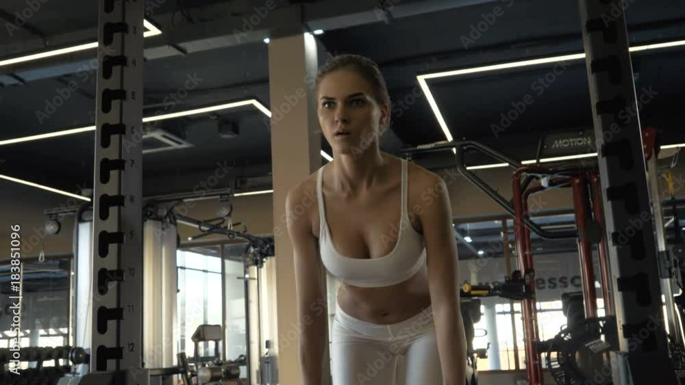 Sports woman leaning with barbell for training buttocks muscle in fitness club front view Sports woman leaning with barbell for training buttocks muscle in fitness club front view