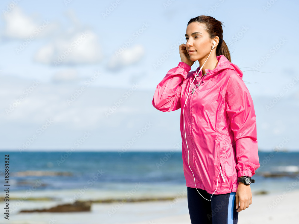 Sporty woman with earphones on the sea coast Sporty woman with earphones on the sea coast