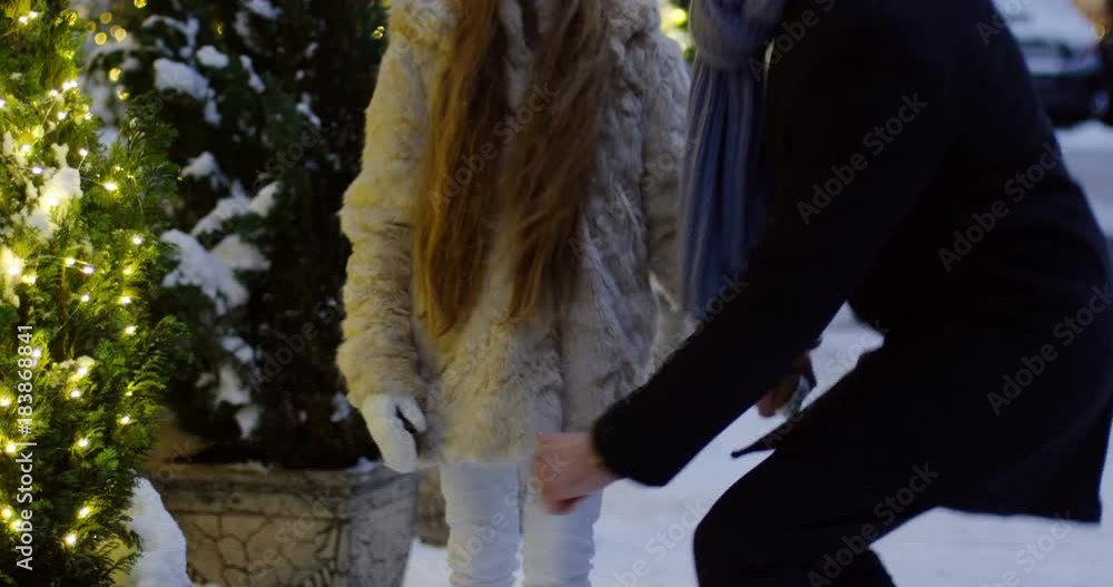 Handsome man walking hand in hand with his lovely daughter on the Christmas decorated street and than father checking if a girl is not cold. Outdoors Handsome man walking hand in hand with his lovely daughter on the Christmas decorated street and than father checking if a girl is not cold. Outdoors