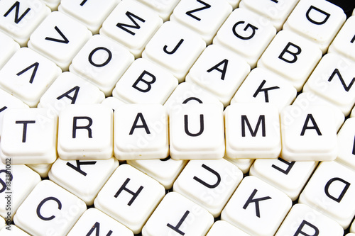 Trauma title text word crossword. Alphabet letter blocks game texture background. White alphabetical letters on black background. White educational toy block with words on board table. Words. photo