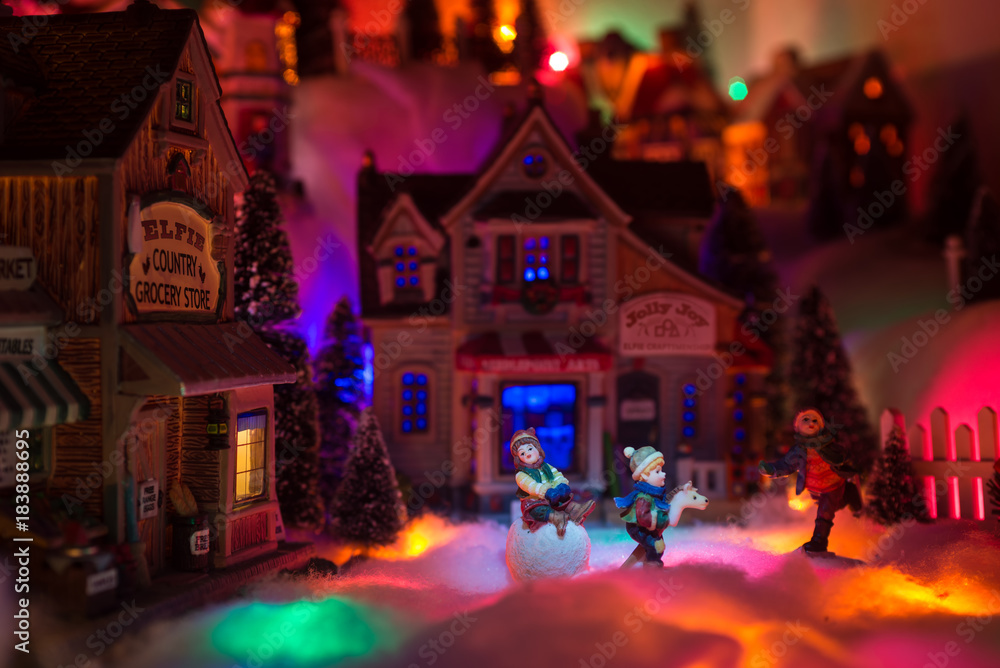 Christmas scenery concept with kids happy playing in snow in the middle of the old town marketplace covered in snow and colorful lights