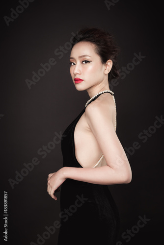 Party. Beautiful sexy asian woman on black background.
