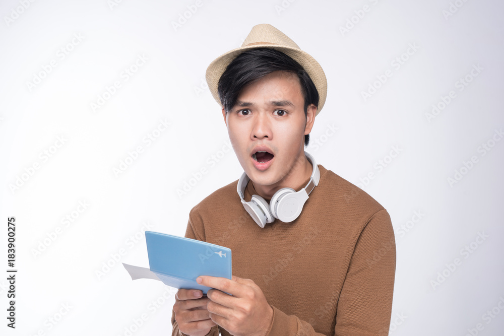 Surprised asian male tourist holding passport over grey background Surprised asian male tourist holding passport over grey background