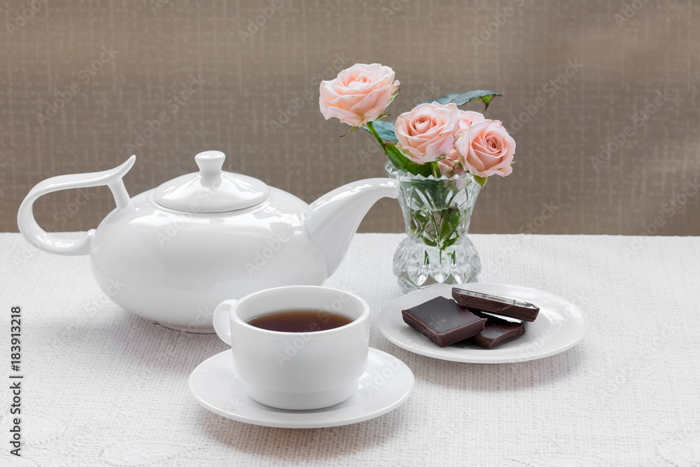 teapot, cup, roses and chocolate on a plate