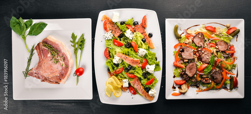 Food. Salads from vegetables, salmon, veal, steak, meat. On a wooden background. Top view. Free space for text.