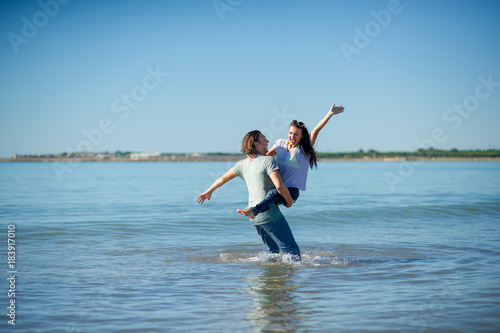 Happy young couple dances in the sea.