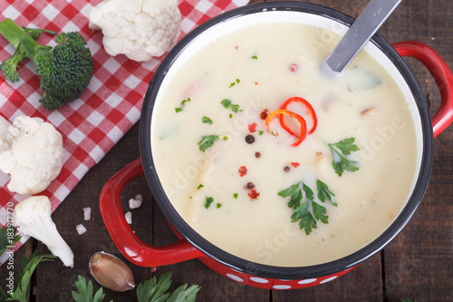 Potato cauliflower soup puree inred pot, top view. Vegetarian healthy food concept photo