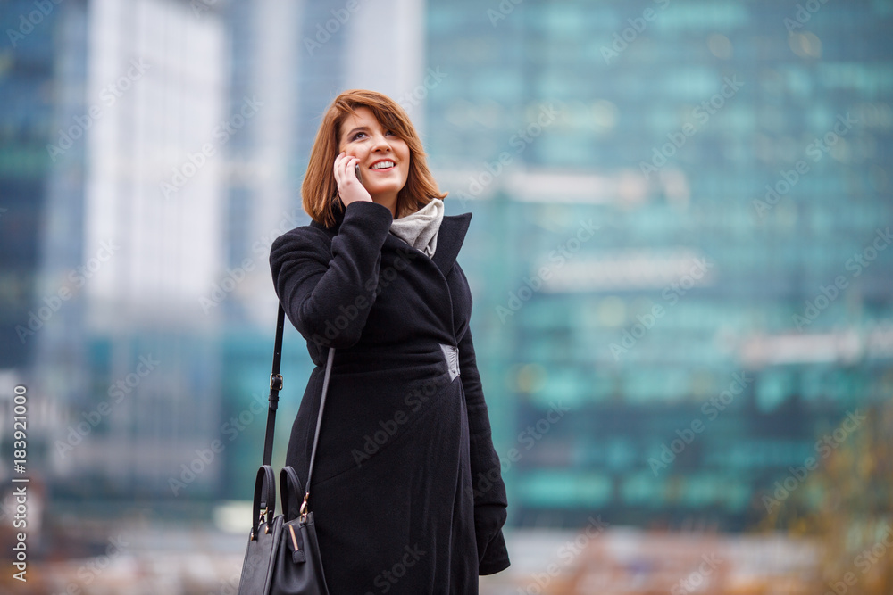 Fototapeta premium Image of girl in black coat talking on phone