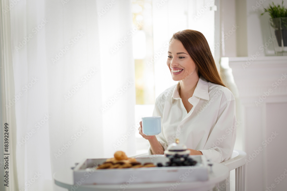 Young woman with cup of coffee sitting at table