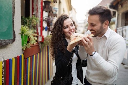 Happy young couple sharing one pizza cut