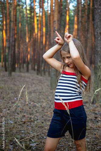 Beautiful little girl in the pine forest in summer.