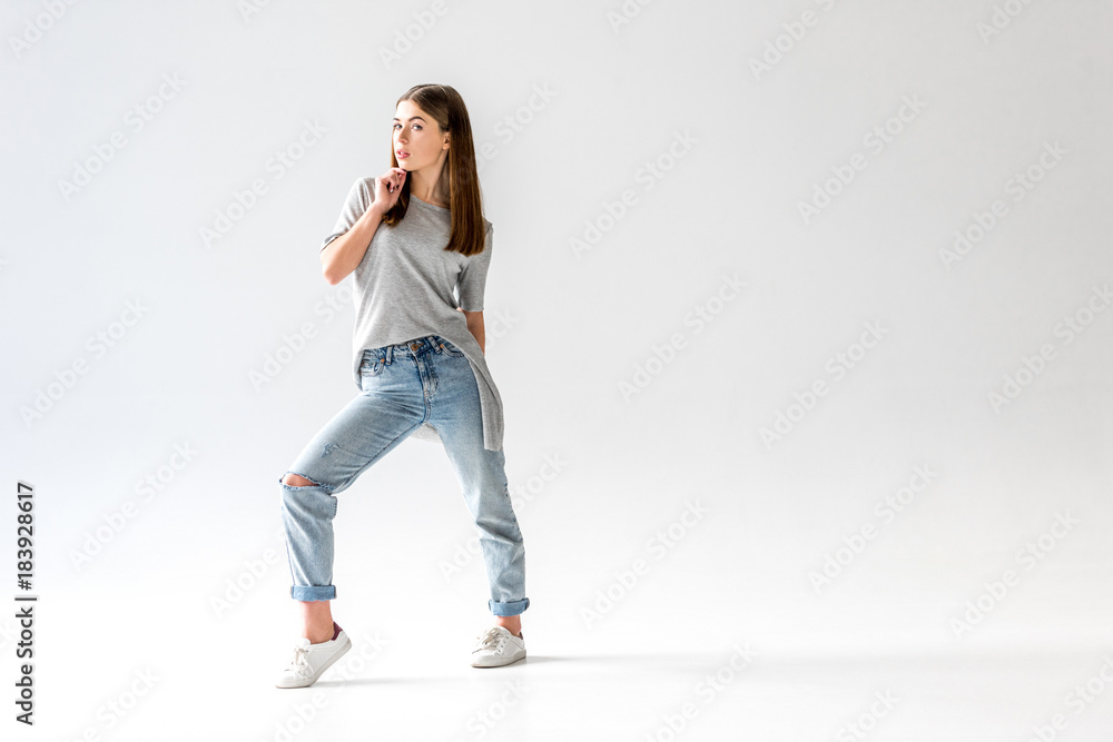 young stylish woman in jeans and grey shirt looking at camera, isolated on white young stylish woman in jeans and grey shirt looking at camera, isolated on white