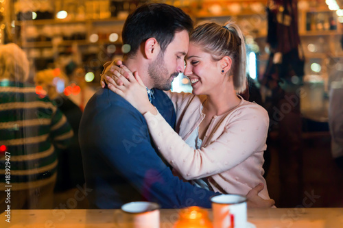 Happy couple hugging at bar and having date