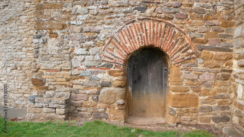 Medieval brick and stone curved arch with wooden door