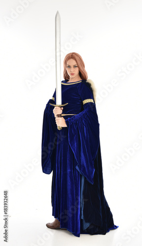  full length portrait of girl wearing long blue velvet gown and fur lined cloak, standing pose on white background.