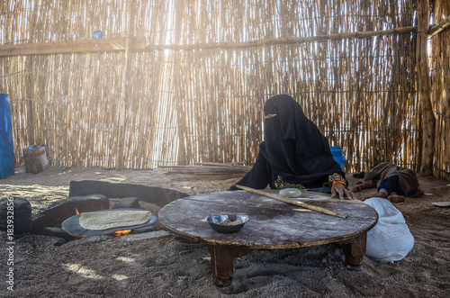 Egypt, Bedouin Village, August 28, 2017: Muslim woman, sitting by the hearth bakes traditional bread for the family
