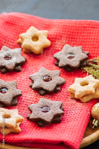 Plate of chocolate and vanilla linzer star cookies with raspberry and orange jam. Festive Christmas dessert.