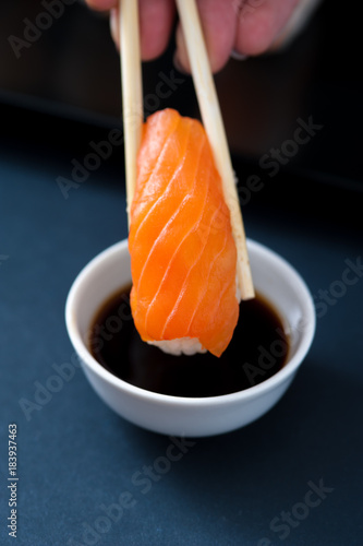 Hands holding Chopstick with Salmon sashimi and soy sauce. Popular Japanese cuisine