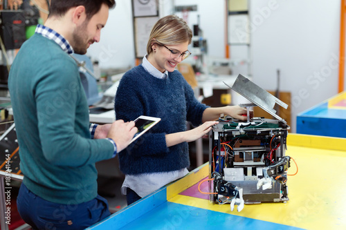 Young students of robotics preparing robot for testing