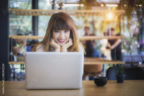 Beautiful happy young curly woman sitting in cafe and using laptop 