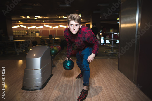 Young man playing bowling with a blue ball for bowling. A man throws a bullet on a stick. © bodnarphoto