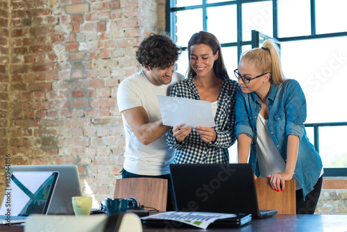 Young business people standing in office, reading business plan for their start-up company photo